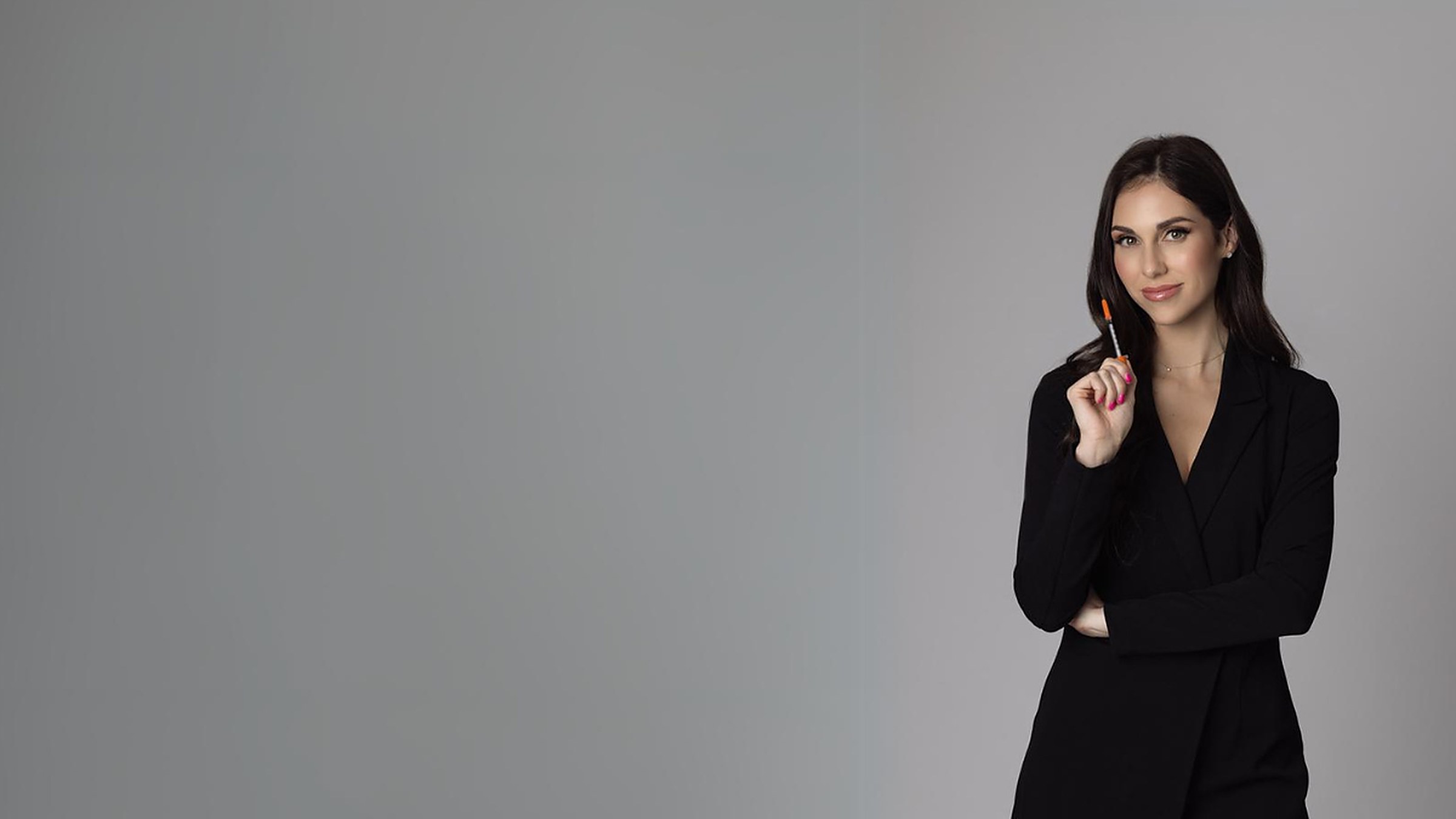 Jessica Donofrio, PA-C, owner of JD Aesthetics, holding a syringe in a studio portrait.